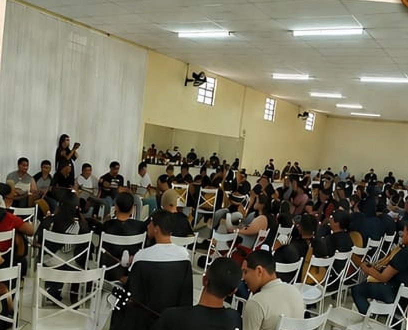 Salão cheio de irmãos com violões em um encontro anterior